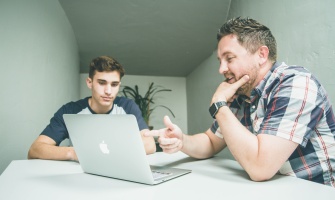 Homme formant un jeune devant un ordinateur